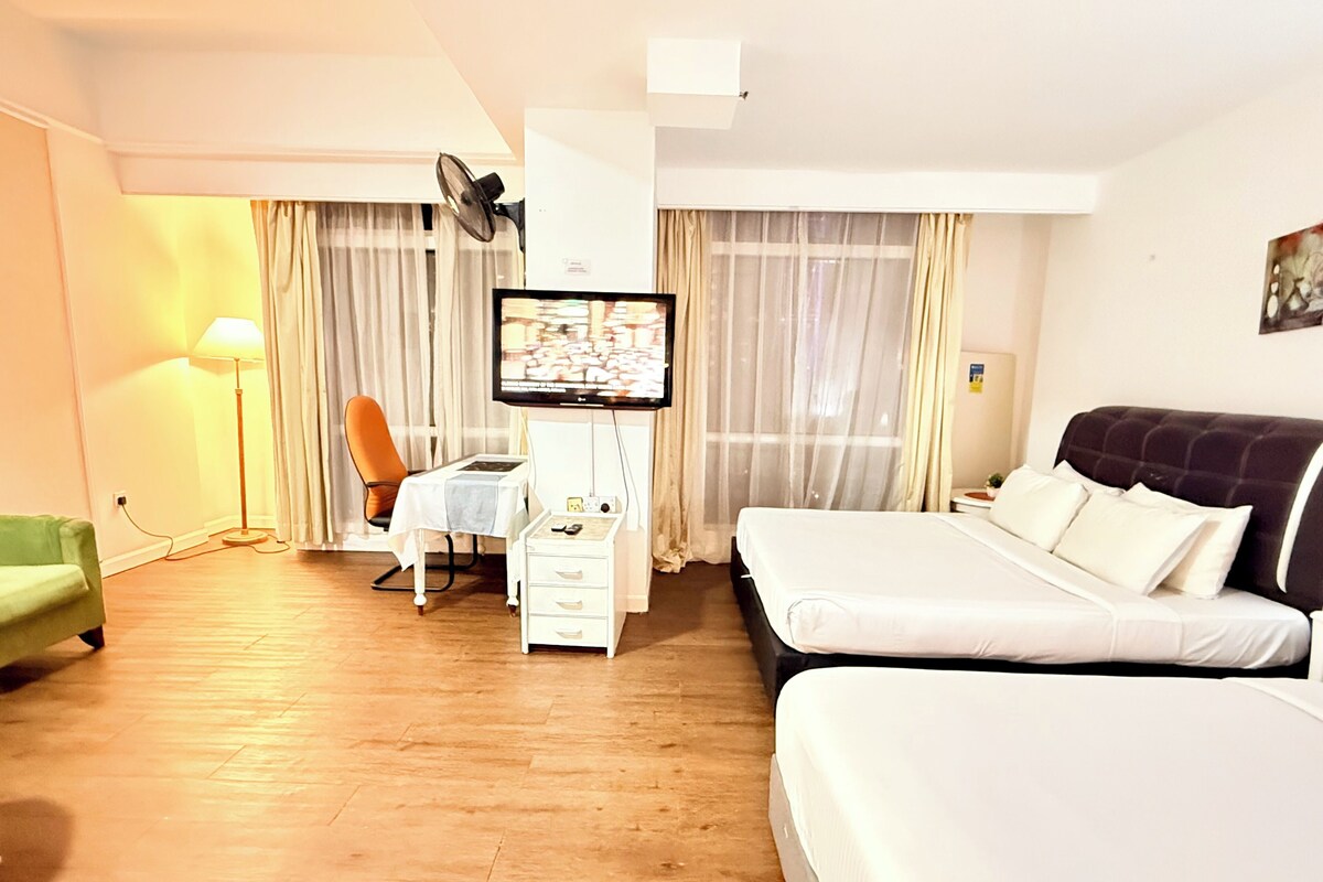 A hotel room with a bed, a desk with a chair, a television, and a lamp.