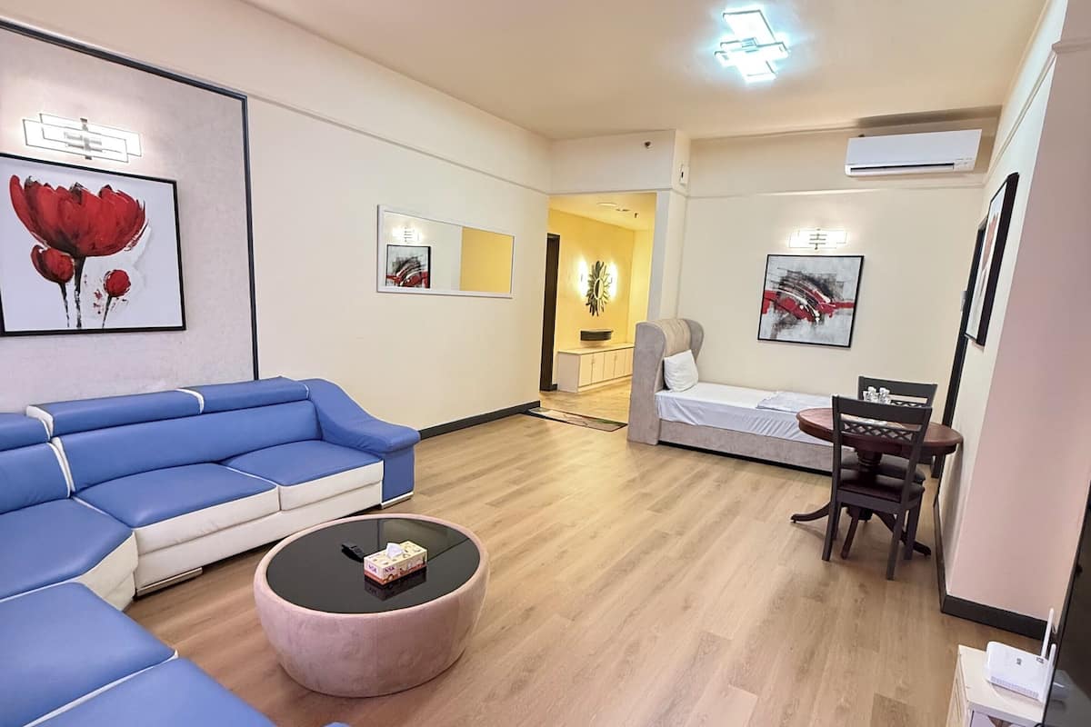 Un salon moderne avec un canapé d’angle, une table basse ronde et un coin repas comprenant une table et des chaises.