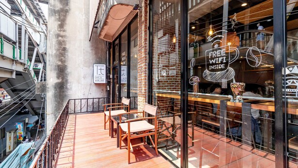 Una cafetería con terraza y vista a la calle, y un cartel que indica conexión WiFi gratuita.