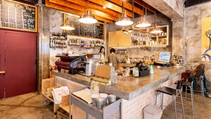 Un bar con techo de madera, luces colgantes y un menú en una pizarra.