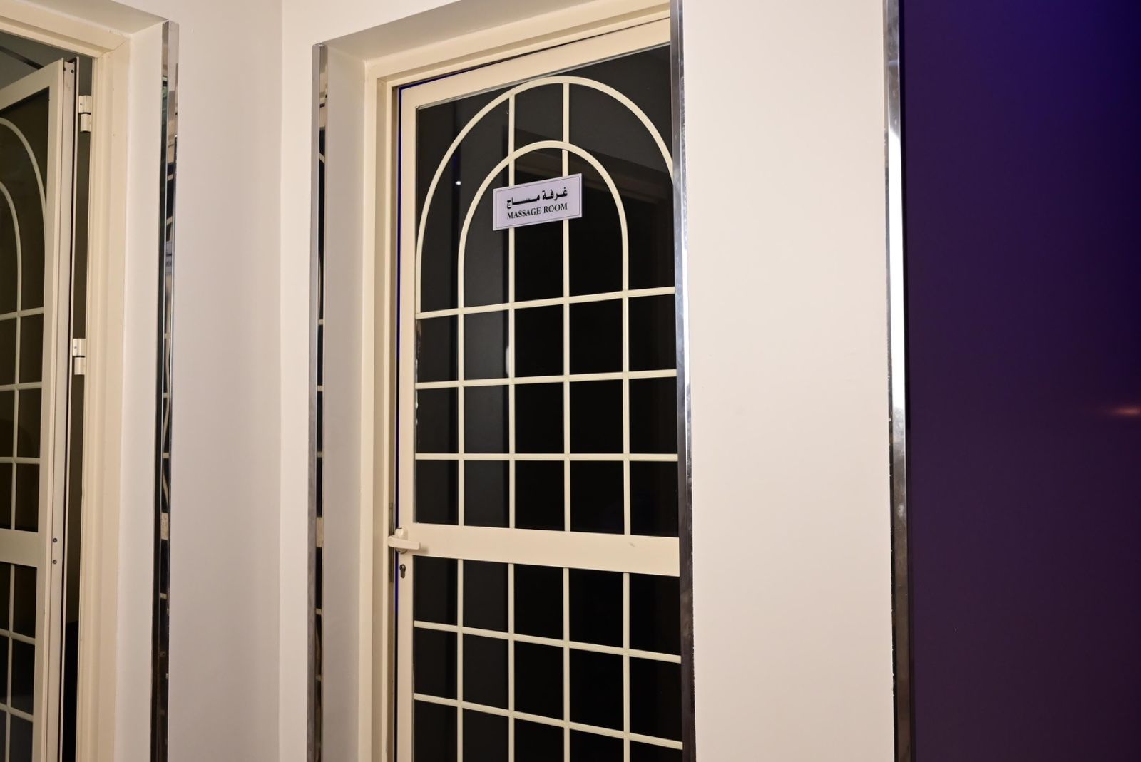 Ein Zimmer mit geschlossener Tür und einem Fenster, an dem ein Schild angebracht ist, das es als Massageräumchen kennzeichnet.