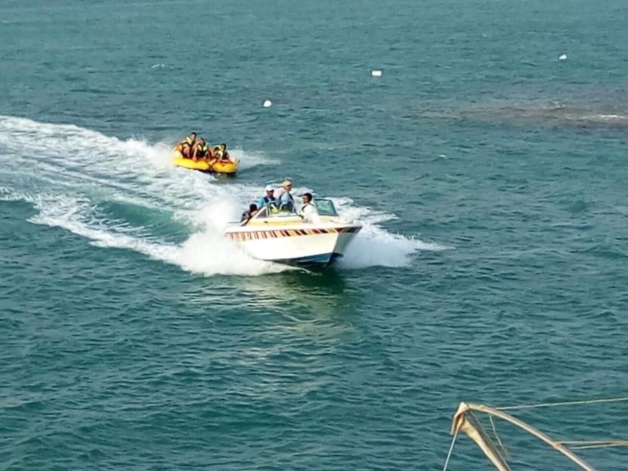A boat with passengers and a wake behind it on a body of water.