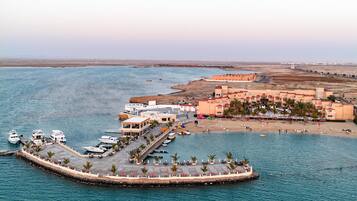 Un complejo turístico frente al mar con un puerto deportivo, playa y una pequeña isla con muelle.