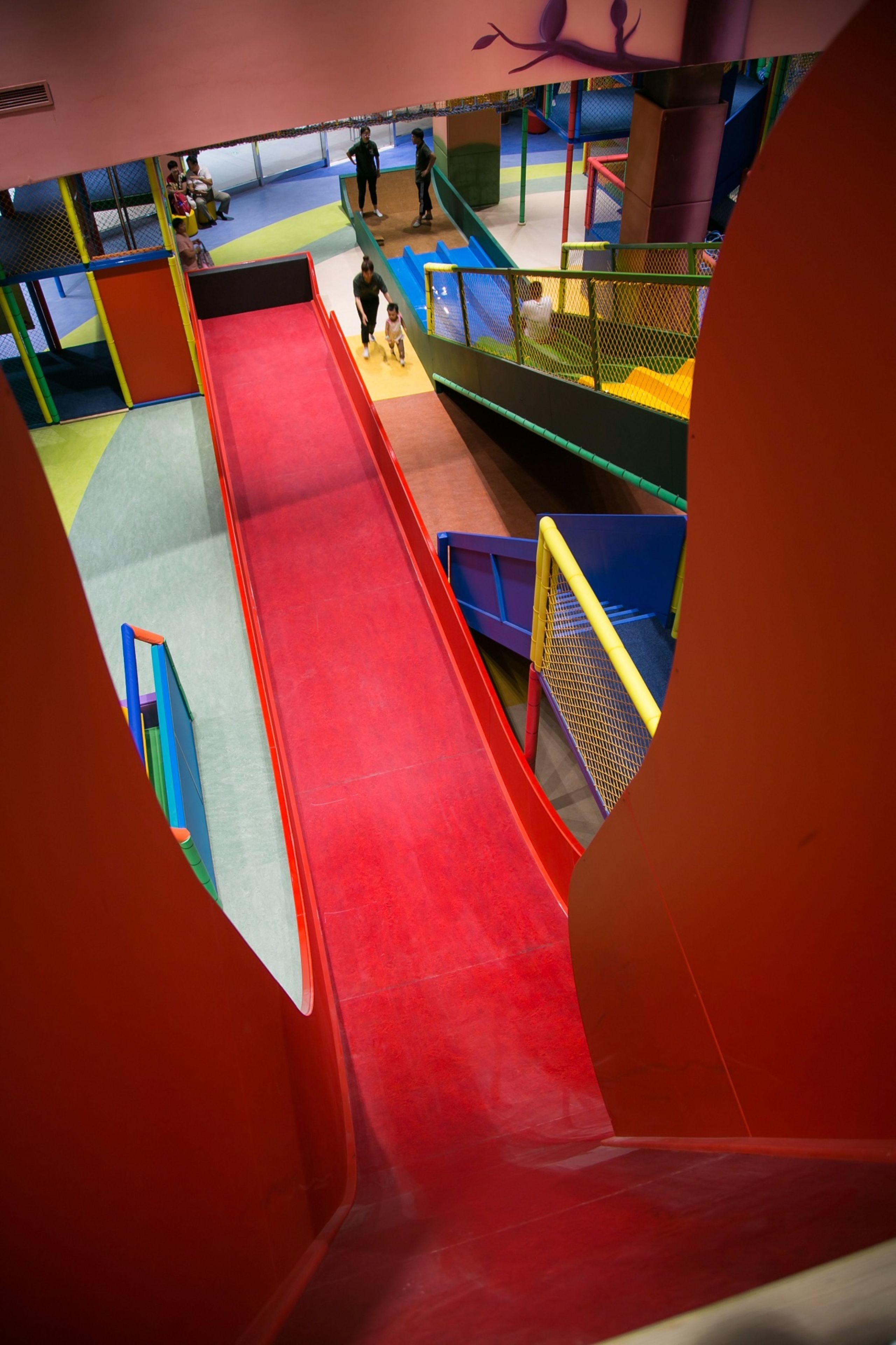 Un área de juegos interior con múltiples niveles, toboganes y estructuras para escalar.
