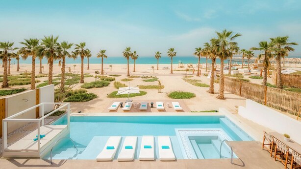 A pool area with lounge chairs and a view of the beach.
