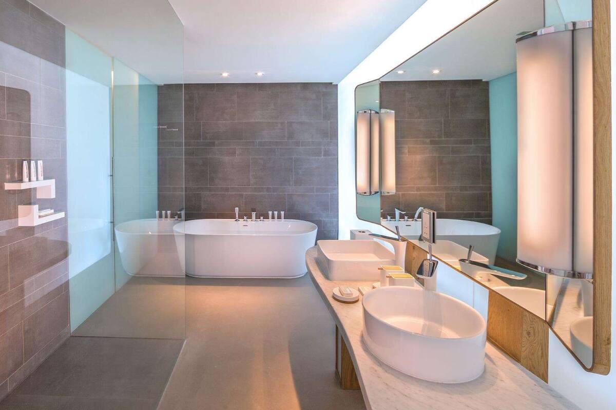 A modern bathroom with two freestanding tubs, a vanity with a sink, and a large mirror.