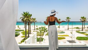 A balcony with a view of the beach, palm trees, and a pool area. - Nikki Beach Resort & Spa Dubai (Dubai)