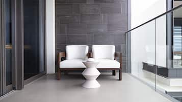 A modern interior with a glass railing, a white sofa, and a unique white table.