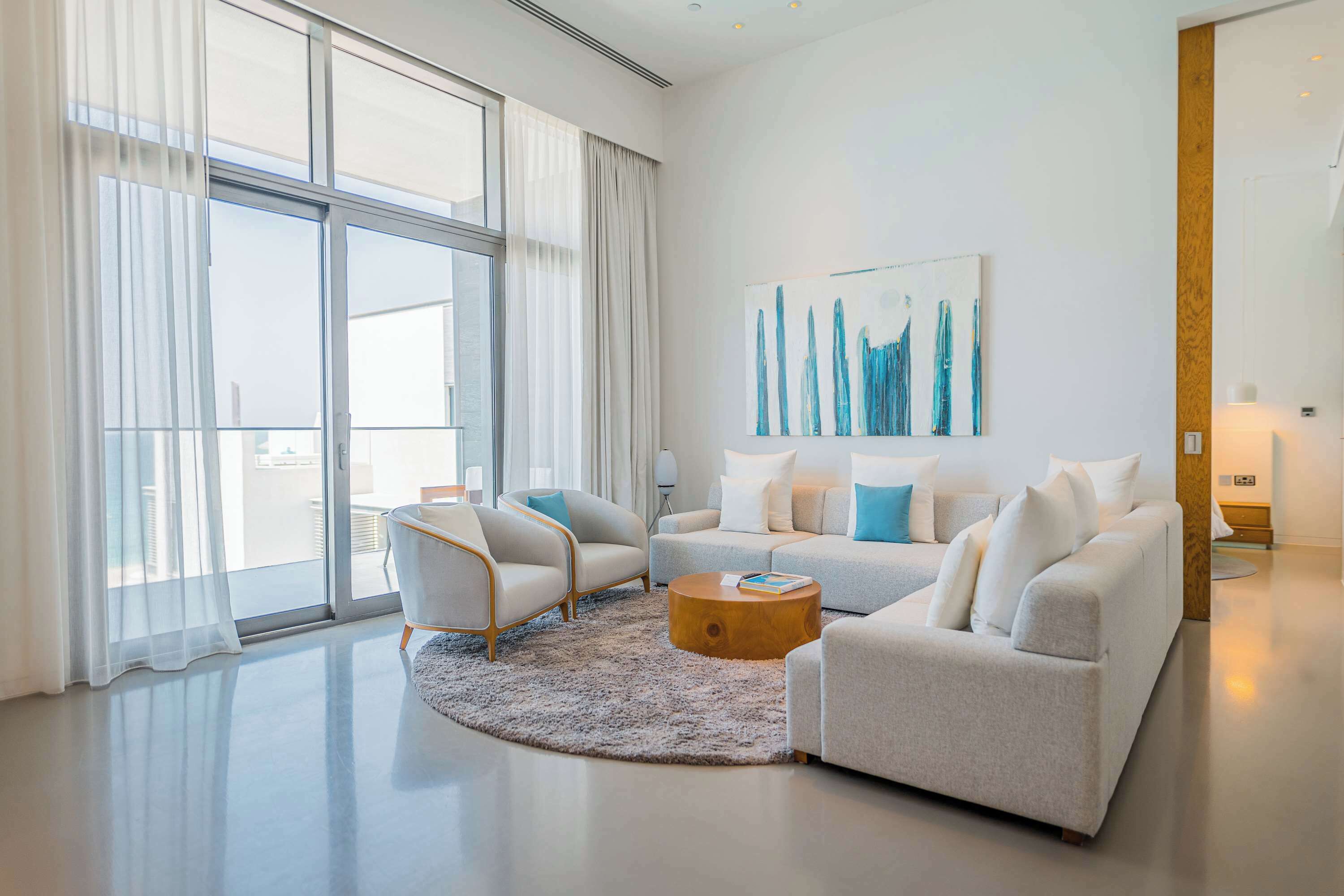 A modern living room with a large window, a sofa set, and a coffee table.