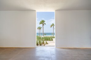 A room with a view of a beach and palm trees.