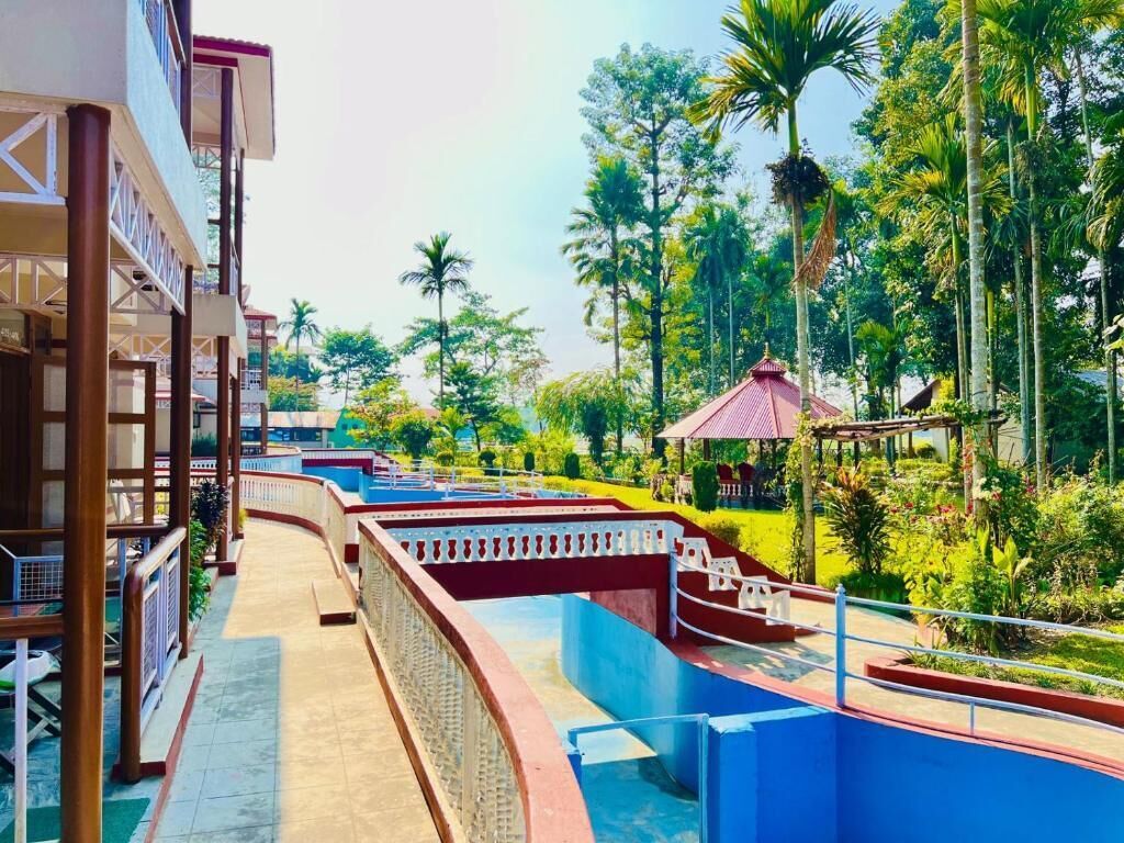 Um resort com área de piscina, galeria coberta e vegetação exuberante.