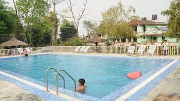 Relax by the pool surrounded by lush greenery and comfortable lounge chairs.