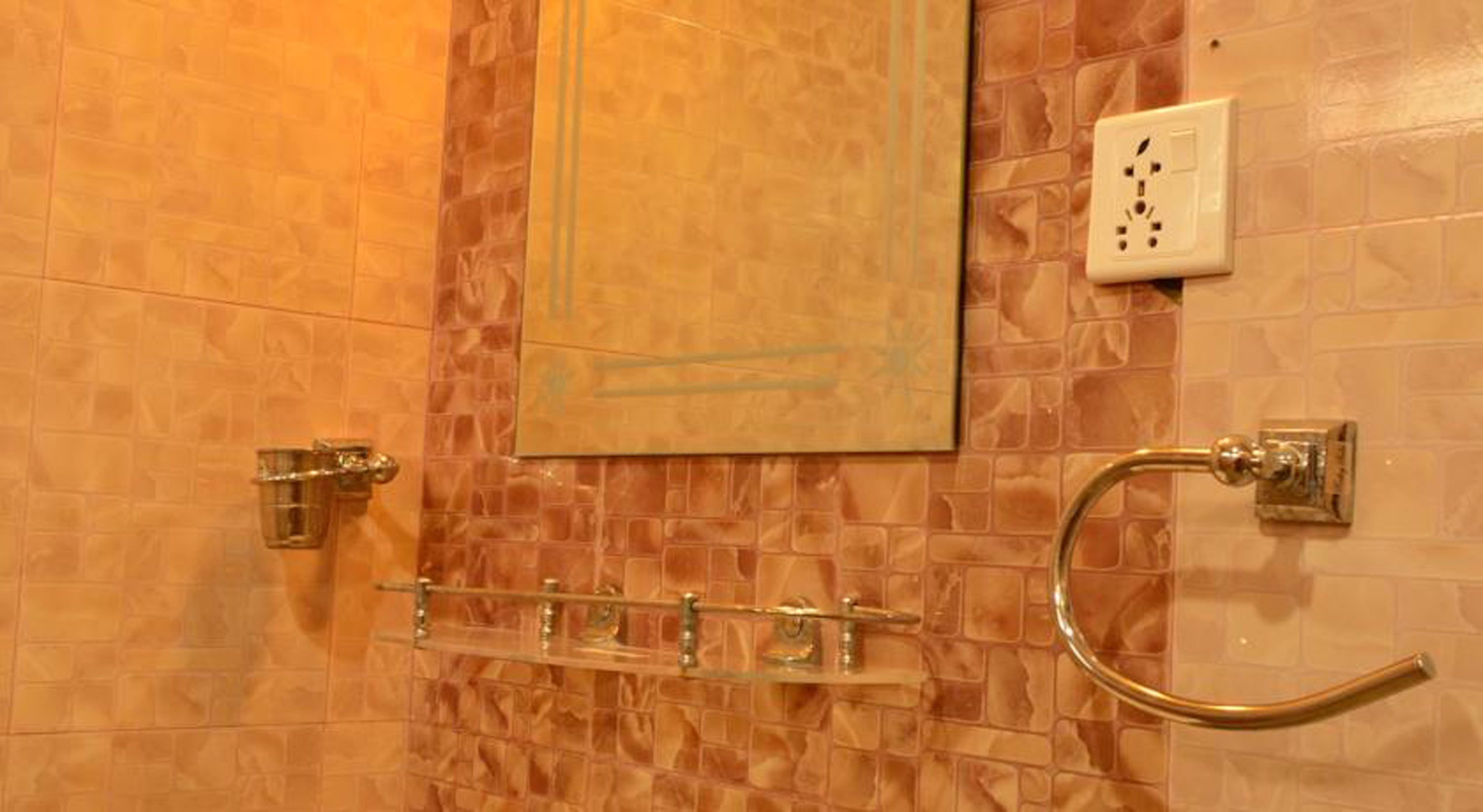 Un baño con pared de azulejos, un perchero, un espejo y un interruptor de luz.