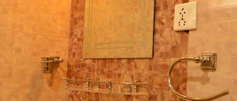 Un baño con pared de azulejos, un perchero, un espejo y un interruptor de luz.