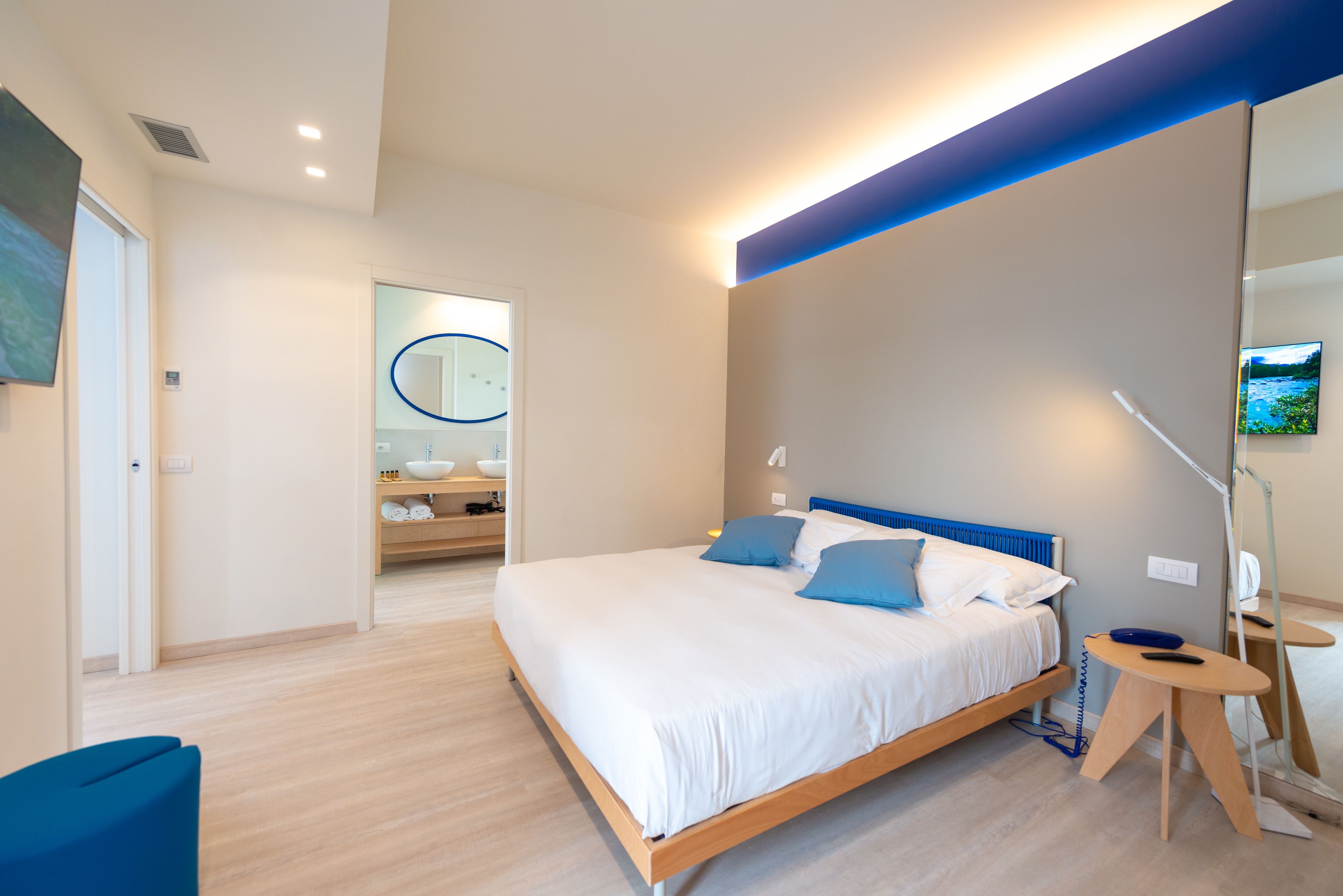 A modern bedroom with a wooden bed, a small bedside table, and a mirror on the wall.