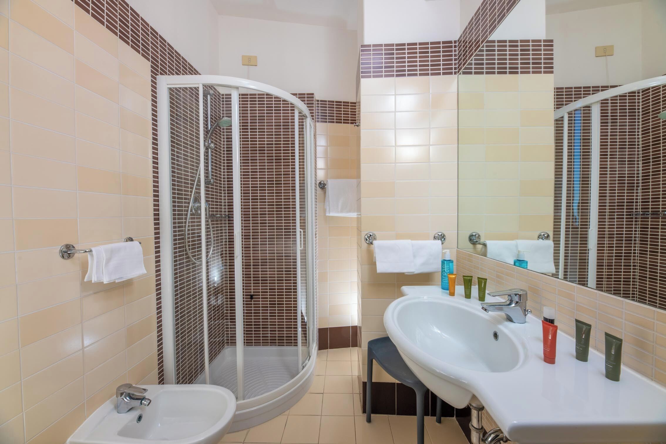 A bathroom with a shower, two sinks, and a large mirror.