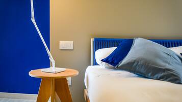 Un dormitorio con una cama, una mesita de noche con lámpara e interruptor de pared.