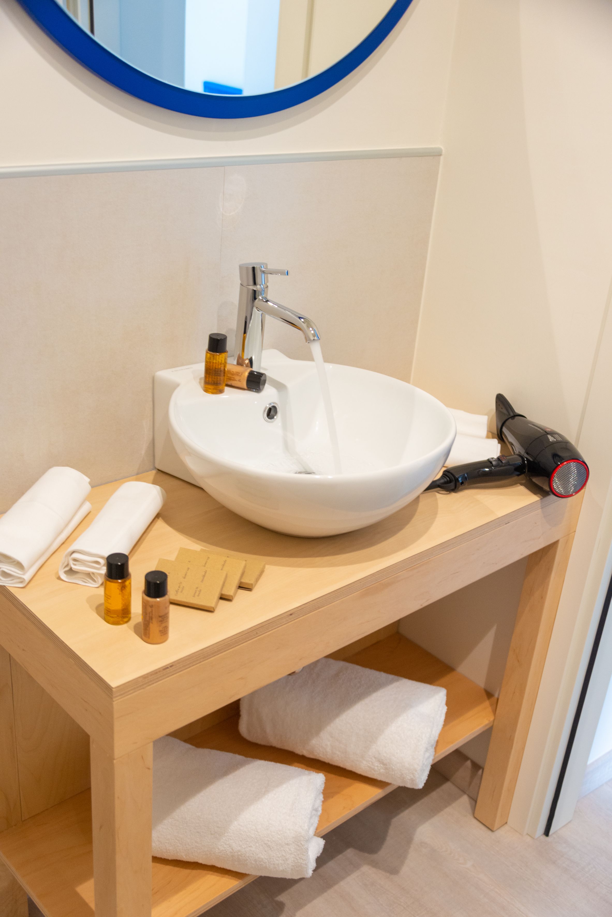 A bathroom with a white sink, a mirror, and a hairdryer on the counter.
