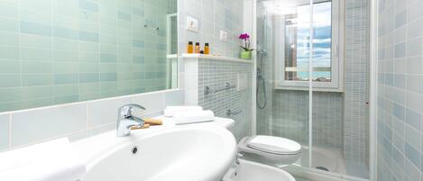 Un baño moderno con un lavamanos grande, un bidé y una ducha con mampara de vidrio.