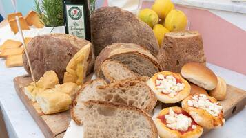 Une variété de pains et de viennoiseries présentés sur une planche en bois, notamment des pains entiers, des tranches de pain et de petits pains garnis de fromage.