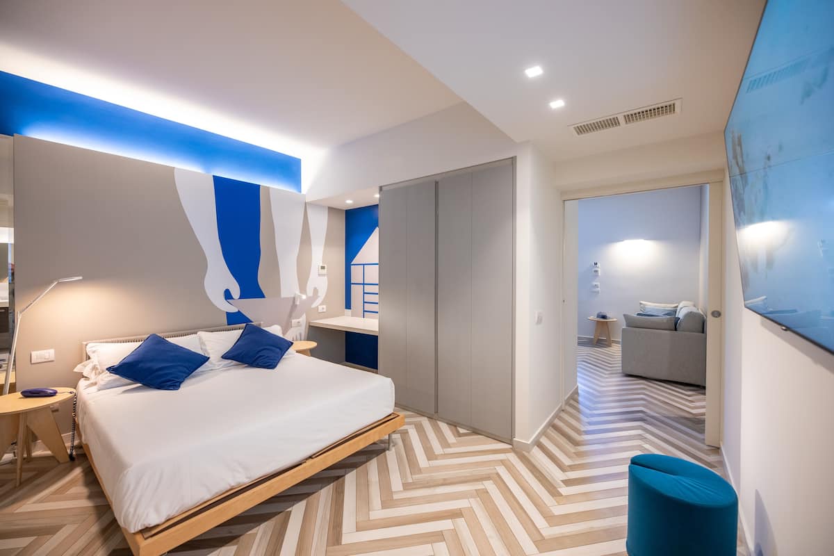A modern bedroom with a bed, bedside table, and a blue accent wall.
