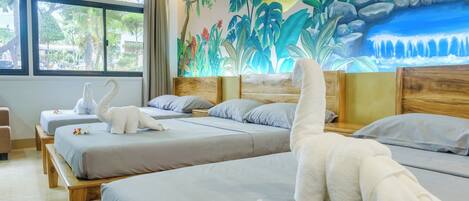 A hotel room with two beds, a mural, and a view of greenery outside.