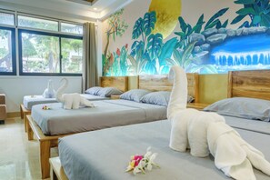 Une chambre d’hôtel avec deux lits, une fresque murale et une vue sur la verdure environnante.