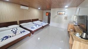 A hotel room with four beds, a wooden ceiling, a flat-screen TV, and a small wooden table with a kettle and cups. - Panglao Kalikasan Dive Resort (Panglao)
