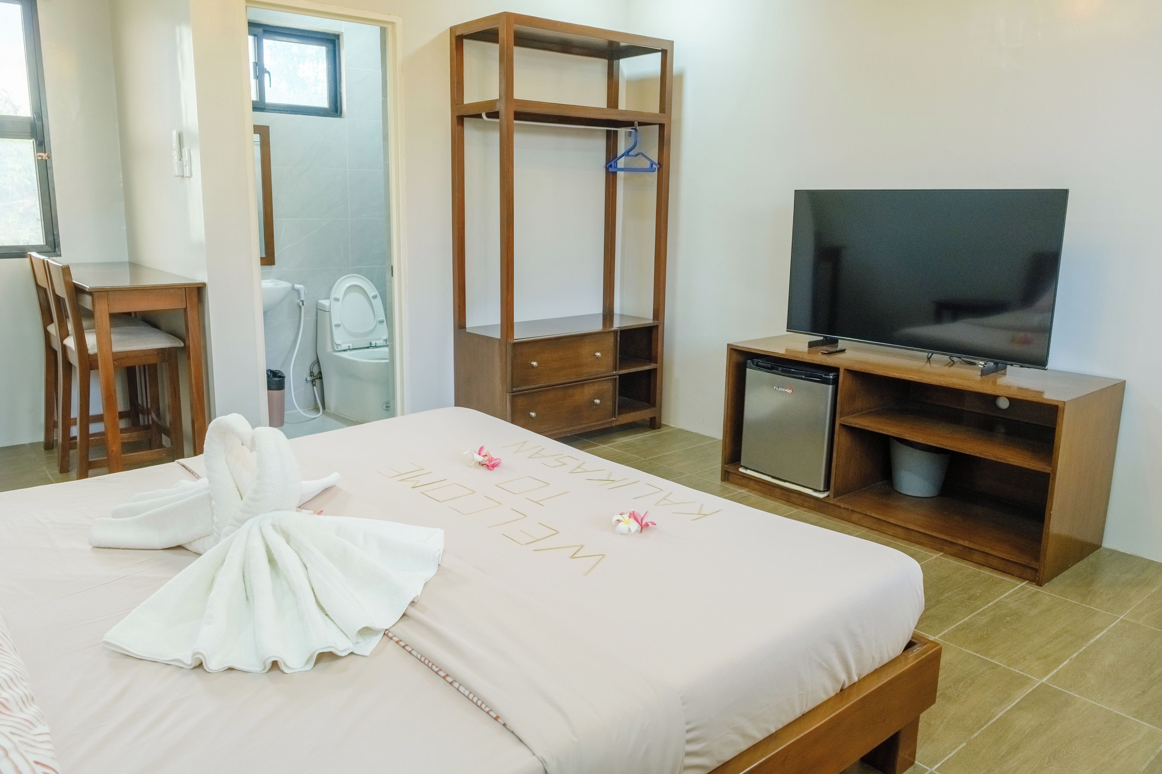 A hotel room with a bed, a desk, a television, and a minibar.
