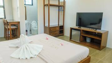 A hotel room with a bed, a desk, a television, and a minibar.