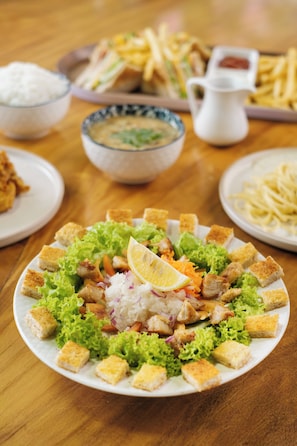 Une table où l'on trouve une variété de plats, notamment une salade avec des croûtons, un bol de soupe et des assiettes de frites.