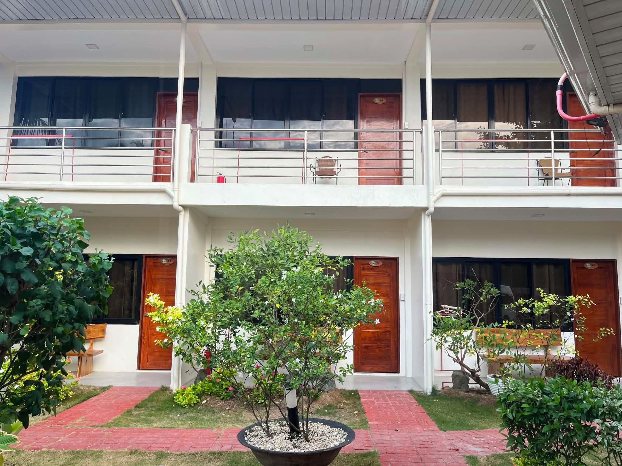 A multi-story building with balconies, a central courtyard with potted plants, and a red brick pathway.