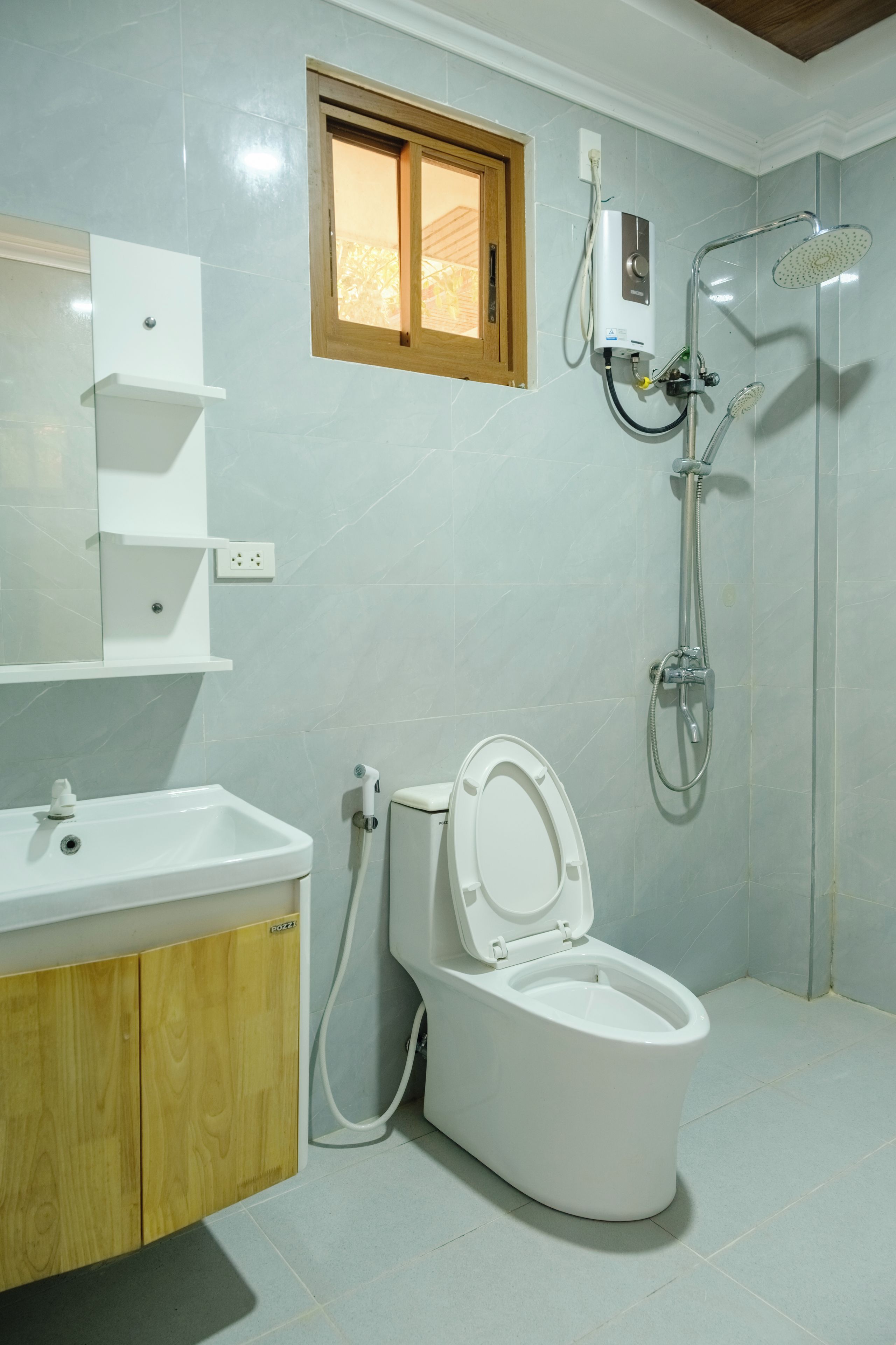 A bathroom with a toilet, a sink, a shower, and a window.