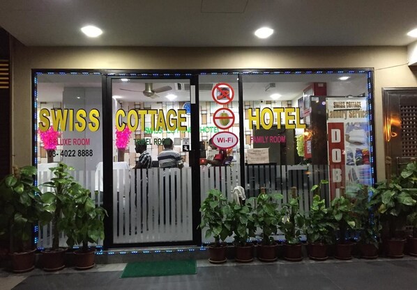 The entrance of a hotel with labeled doors for 'SWISS COTTAGE DELUXE ROOM' and 'HOTEL FAMILY ROOM'. - Swiss Cottage Hotel (Kuala Lumpur)