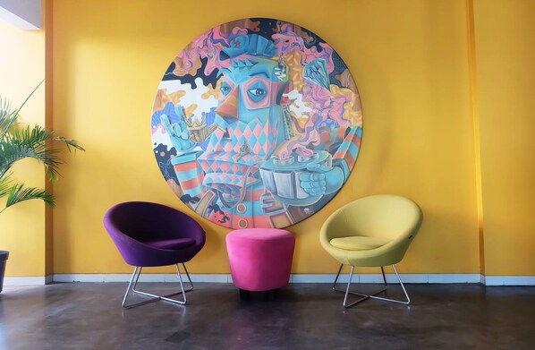Une pièce avec un mur jaune, un grand tableau abstrait et deux chaises modernes.