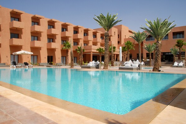 Una piscina al aire libre, sombrillas, tumbonas