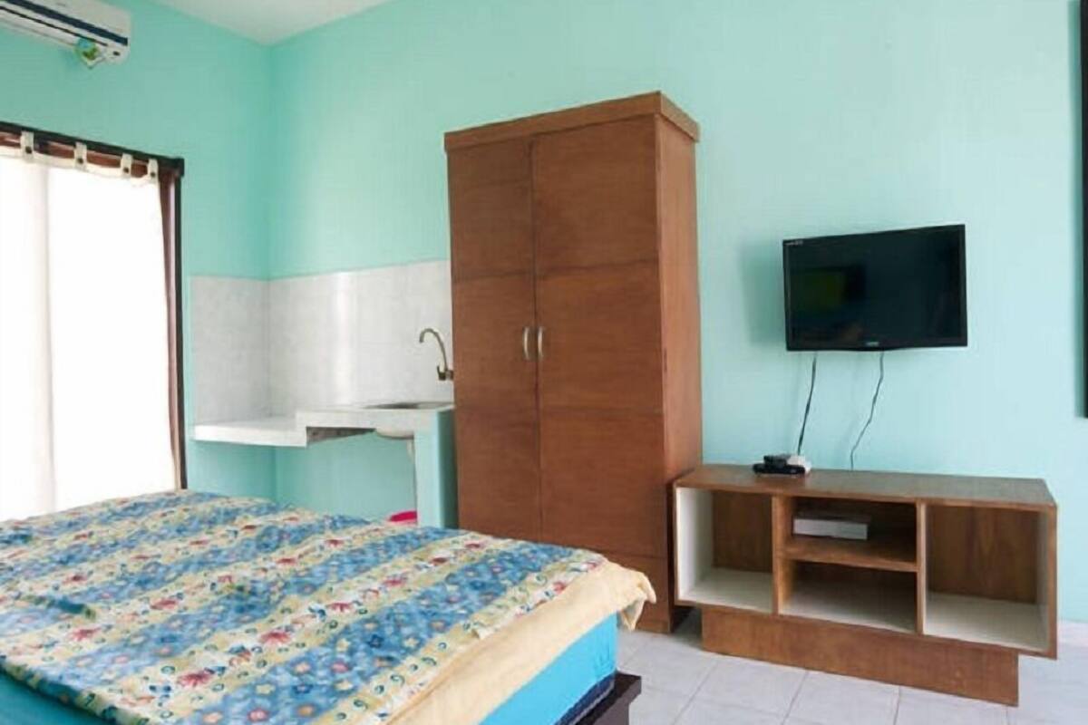 Un dormitorio con una cama, un armario de madera, un televisor y un escritorio pequeño.