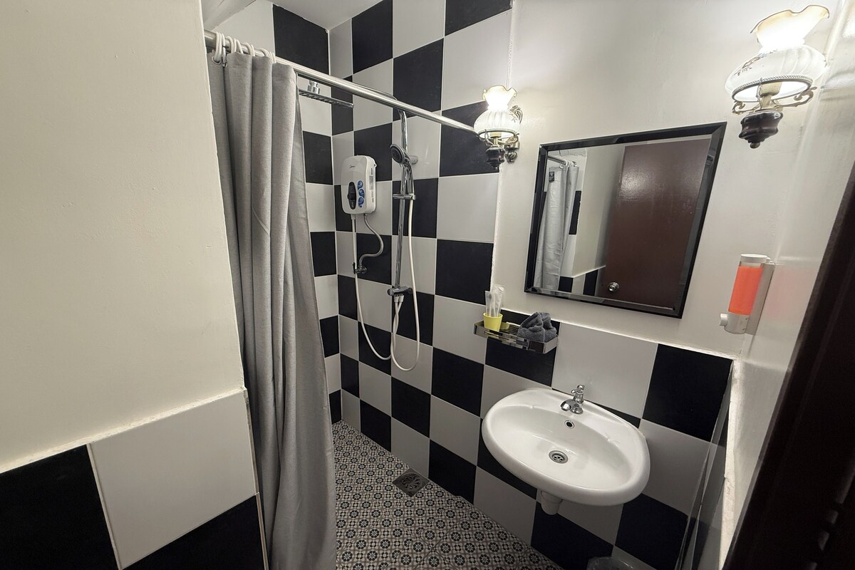 A bathroom with a checkered floor, a white sink, a mirror, and a shower with a curtain.