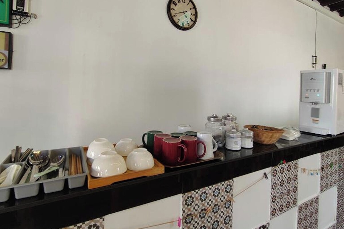 A kitchen area with a clock, utensils, mugs, and a coffee maker.
