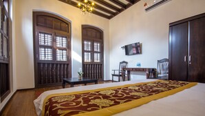 A hotel room with a large bed, wooden furniture, a chandelier, and a television on the wall. - D'Nice Heritage House (George Town)