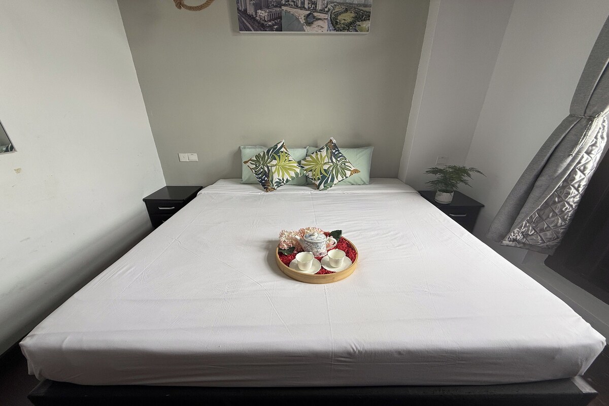 A neatly made bed with a tray of tea set and decorative pillows.