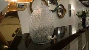 A black countertop with a gold lamp, a crystal vase, and multiple mirrors on the wall. - D'Nice Heritage House (George Town)