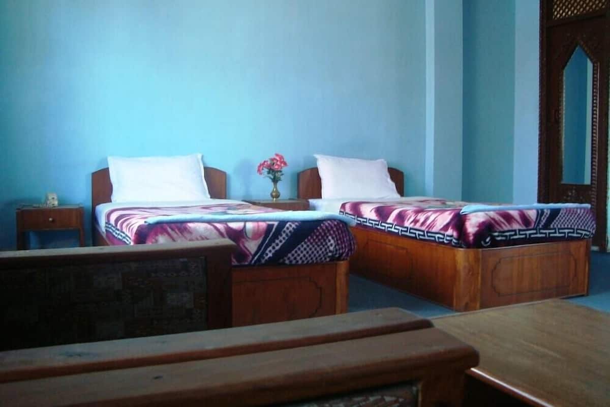 A room with two wooden beds, a wooden desk, and a small table.