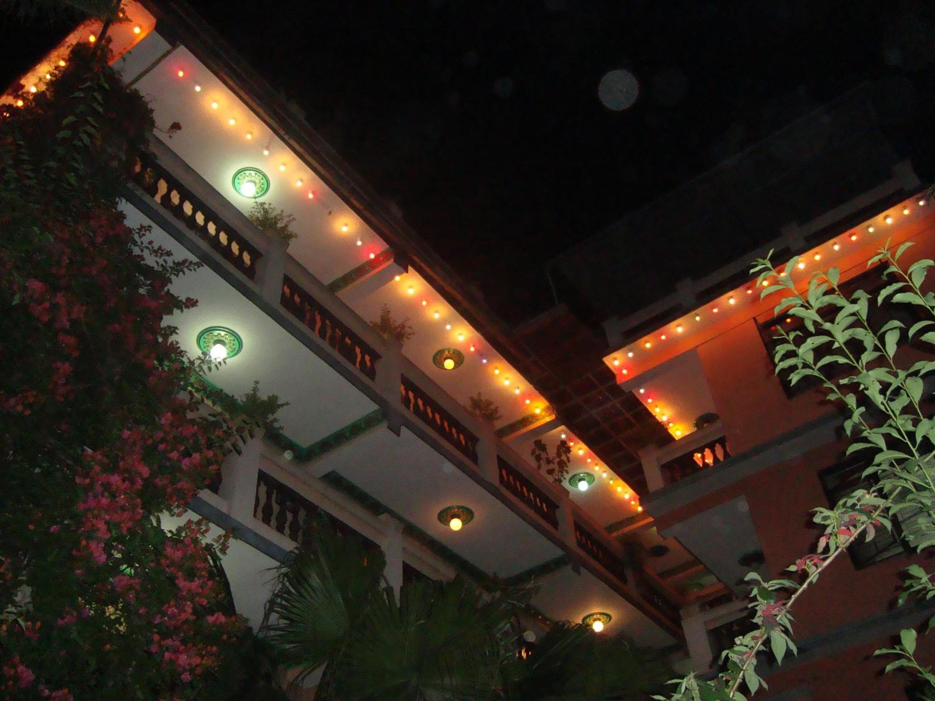 A multi-story building with balconies, string lights, and decorative ceiling lights.