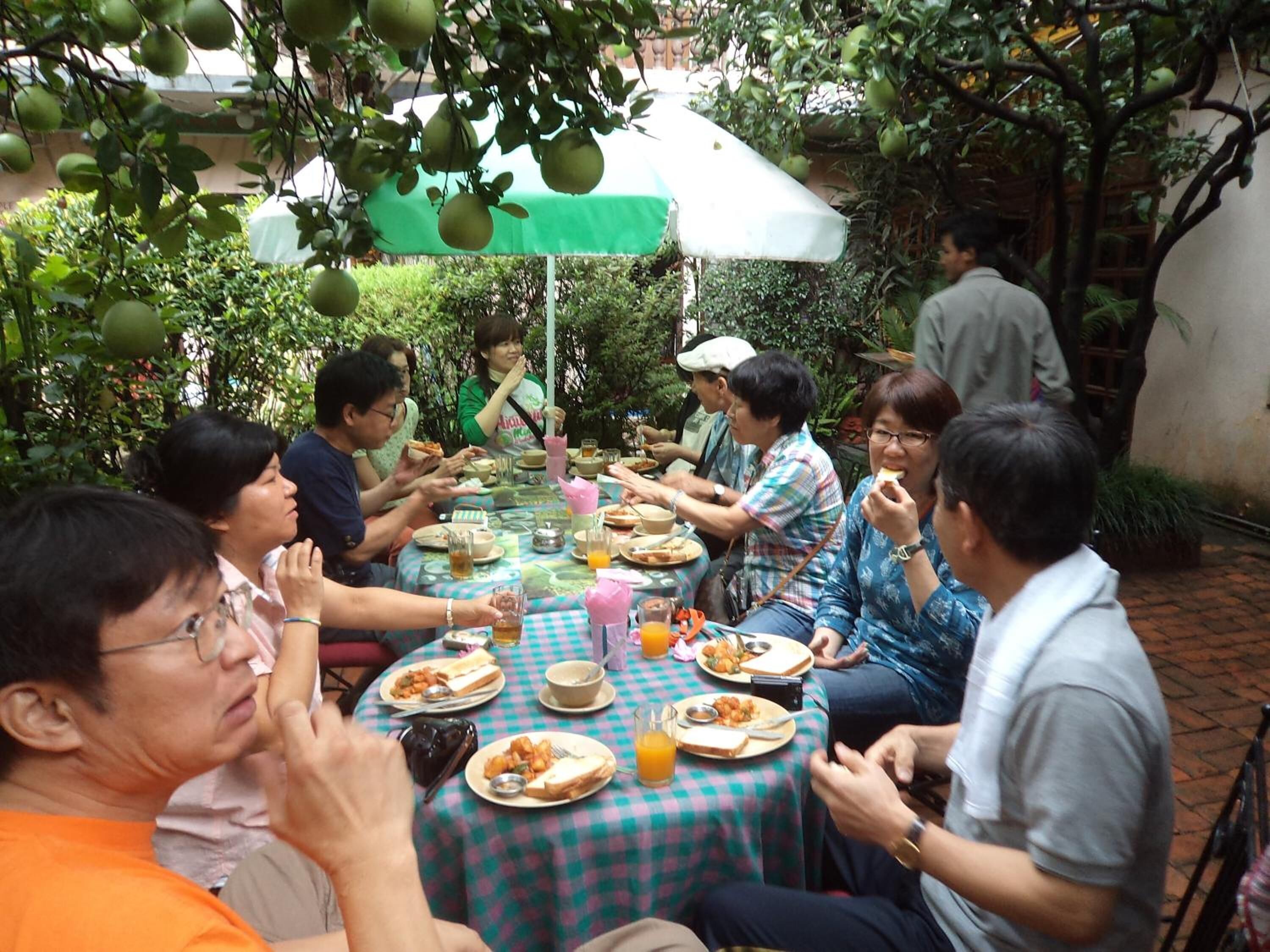 A group of people dining outdoors at a table with a checkered tablecloth.