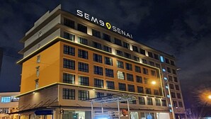 Un hôtel à plusieurs étages, reconnaissable à son enseigne bien visible où l’on peut lire « SEM9 SENAI ».