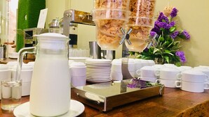 Un buffet avec un pichet, des assiettes, des tasses et un distributeur de céréales.
