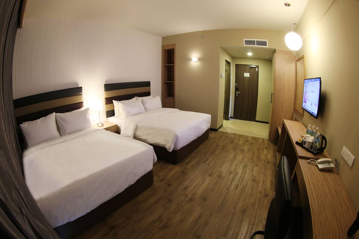 A hotel room with two beds, a desk with a phone, and a TV.