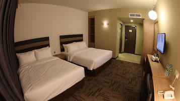 Une chambre d’hôtel avec deux lits, un bureau avec un téléphone, une télévision et une porte de salle de bain.