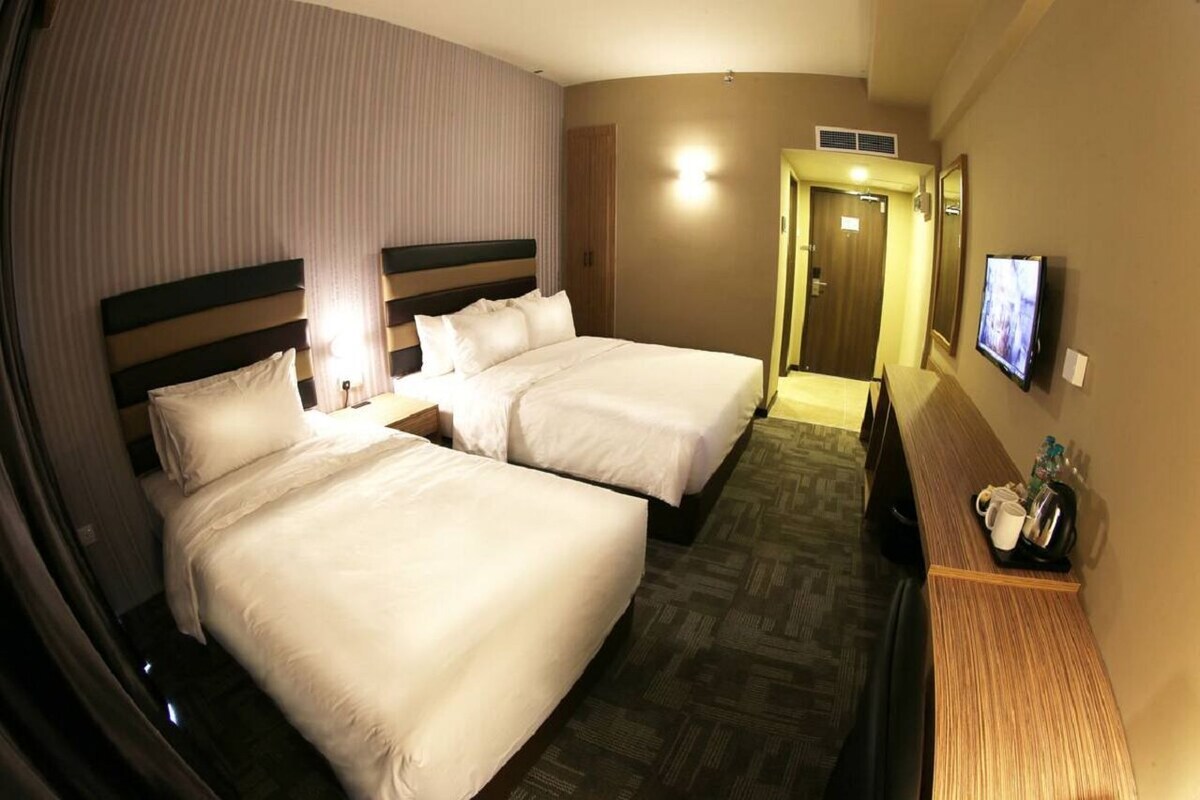 Ein Hotelzimmer mit zwei Betten, einem Fernseher und einem Empfangstresen.